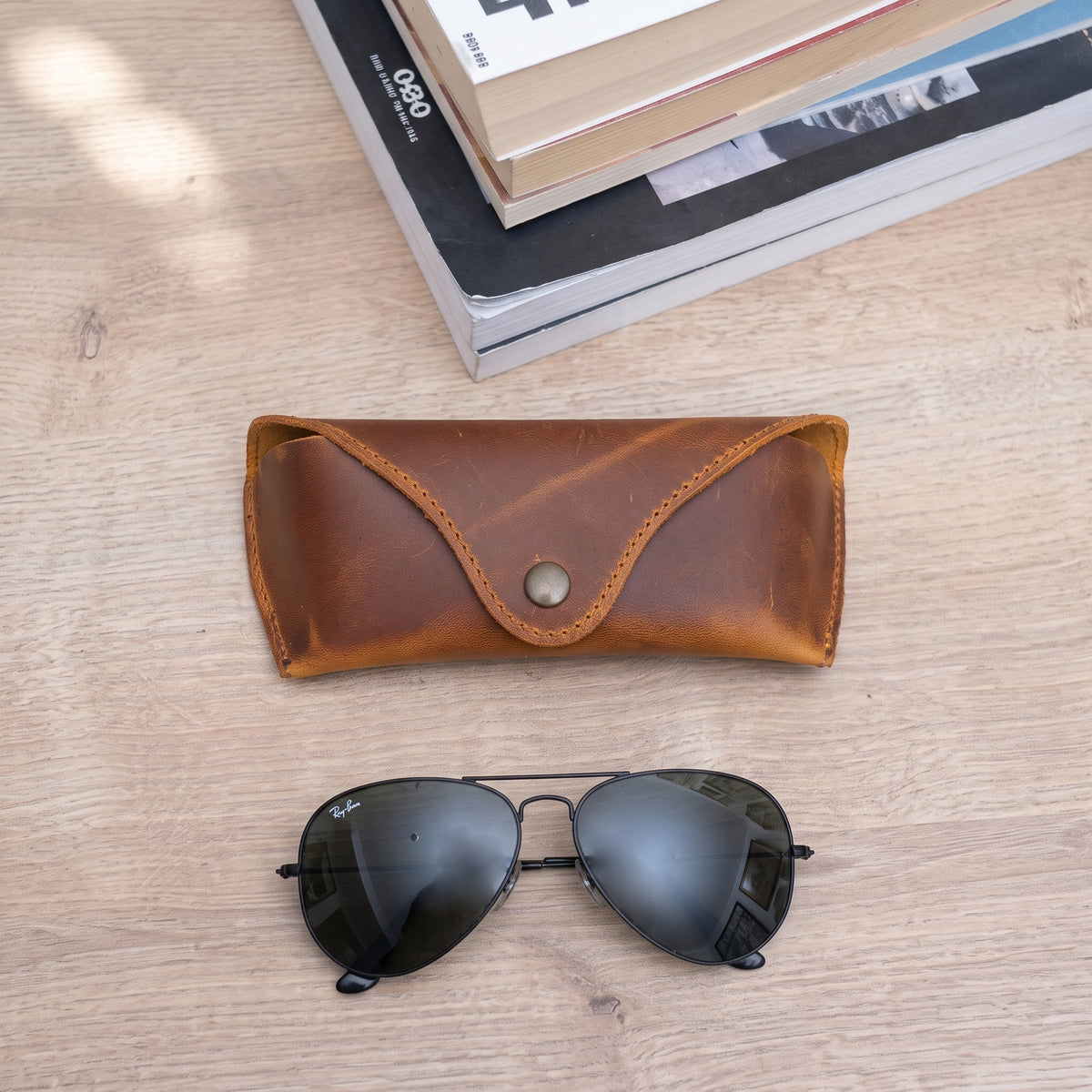 Lucent handcrafted  brown Crazy Horse leather sunglasses case with snap closure and aviator glasses on desk - Yubello