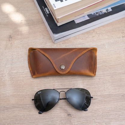 Lucent handcrafted  brown Crazy Horse leather sunglasses case with snap closure and aviator glasses on desk - Yubello